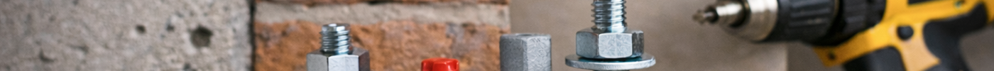 Anclajes metálicos y tacos de fijación sobre fondo de hormigón y ladrillo, junto a un taladro, para guía sobre elección de anclaje según soporte y carga.